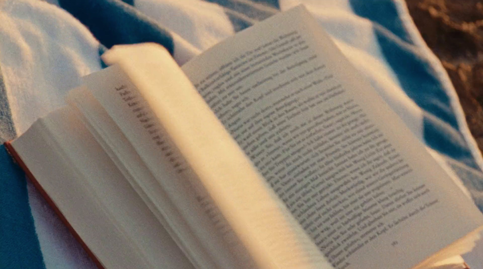 an open book laying on top of a blue and white blanket