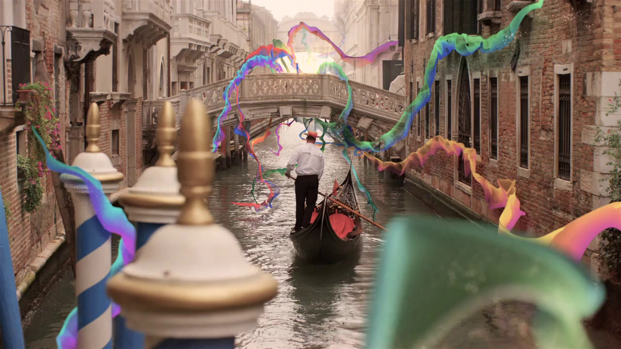 a man riding a boat down a canal under a bridge