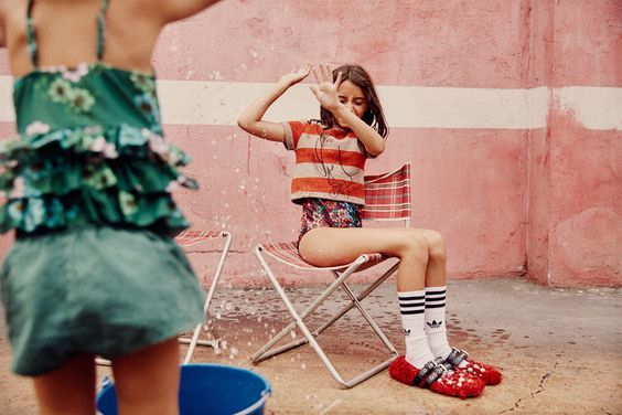 a girl sitting in a chair in front of a pink wall