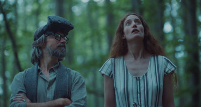 a woman standing next to a man in a forest