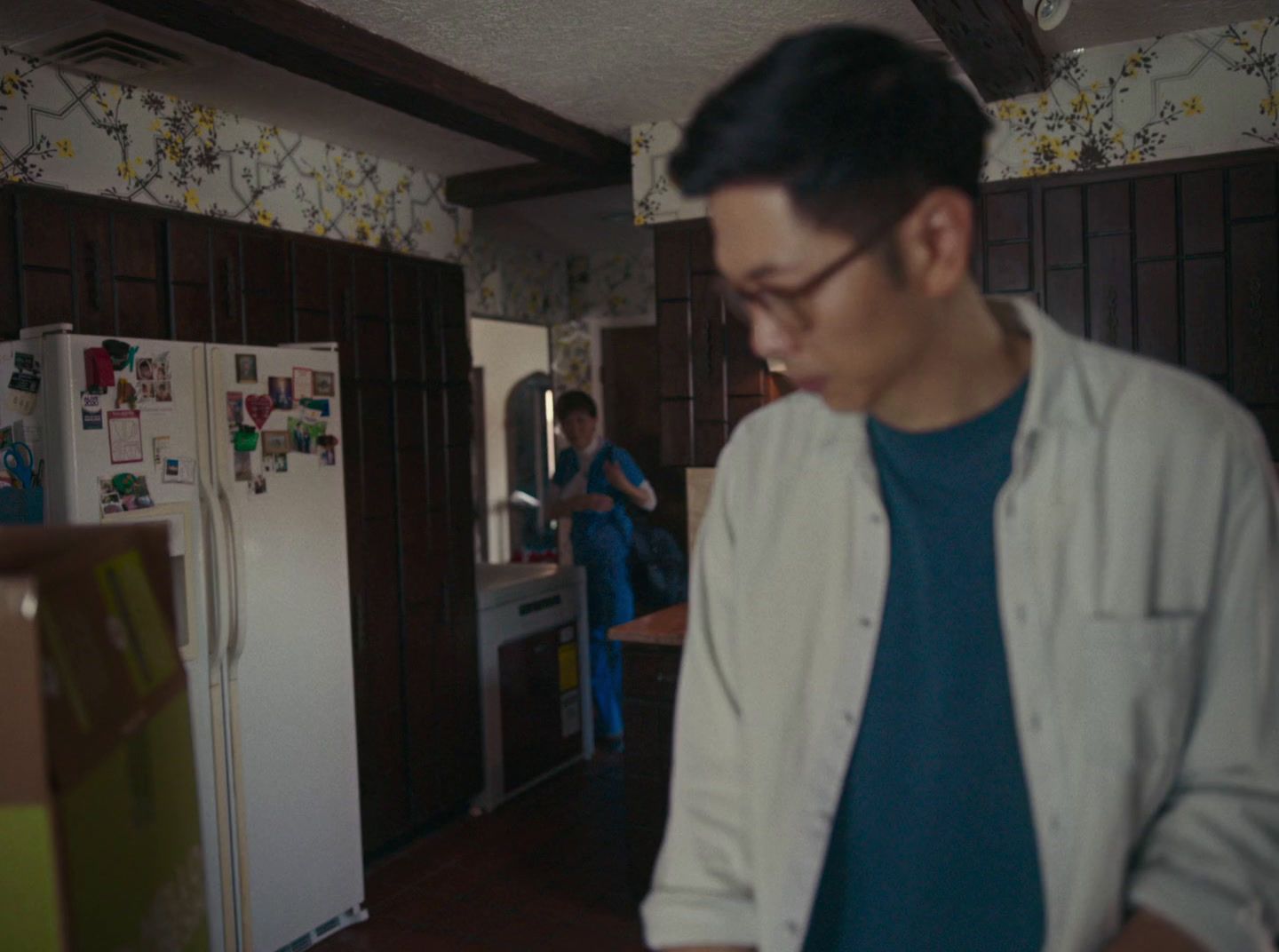 a man standing in a kitchen next to a refrigerator