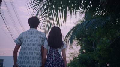 a man and a woman standing next to each other under a palm tree