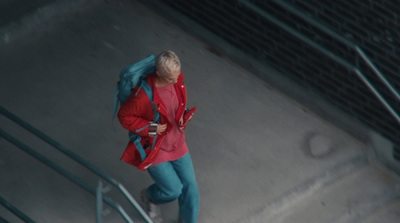 a woman in a red jacket and blue pants walking down a flight of stairs