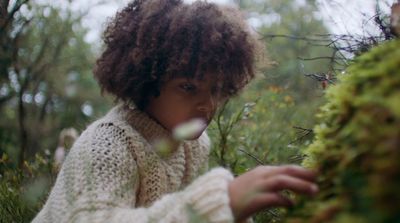 a woman in a white sweater is holding a plant