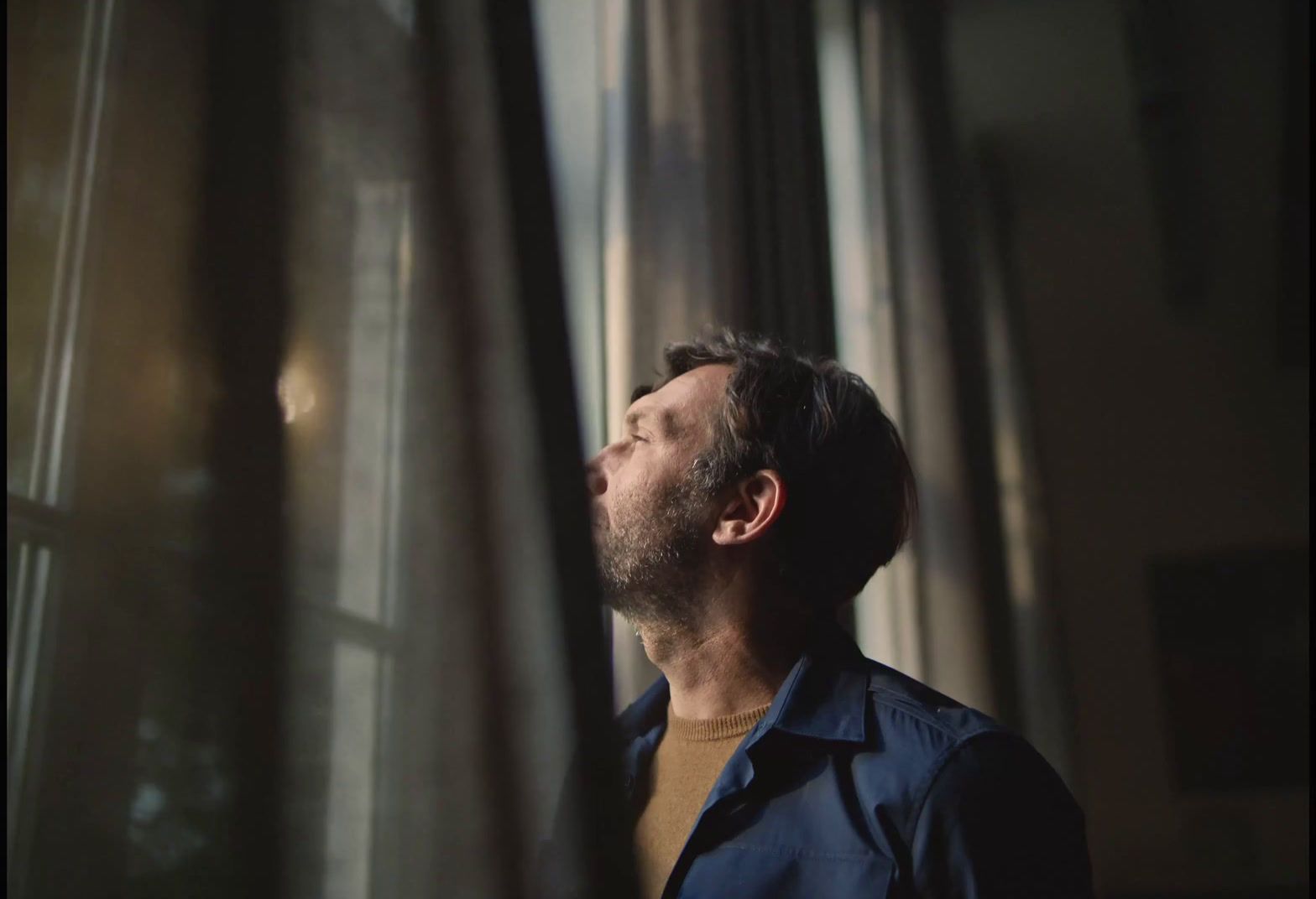 a man standing in front of a window looking up