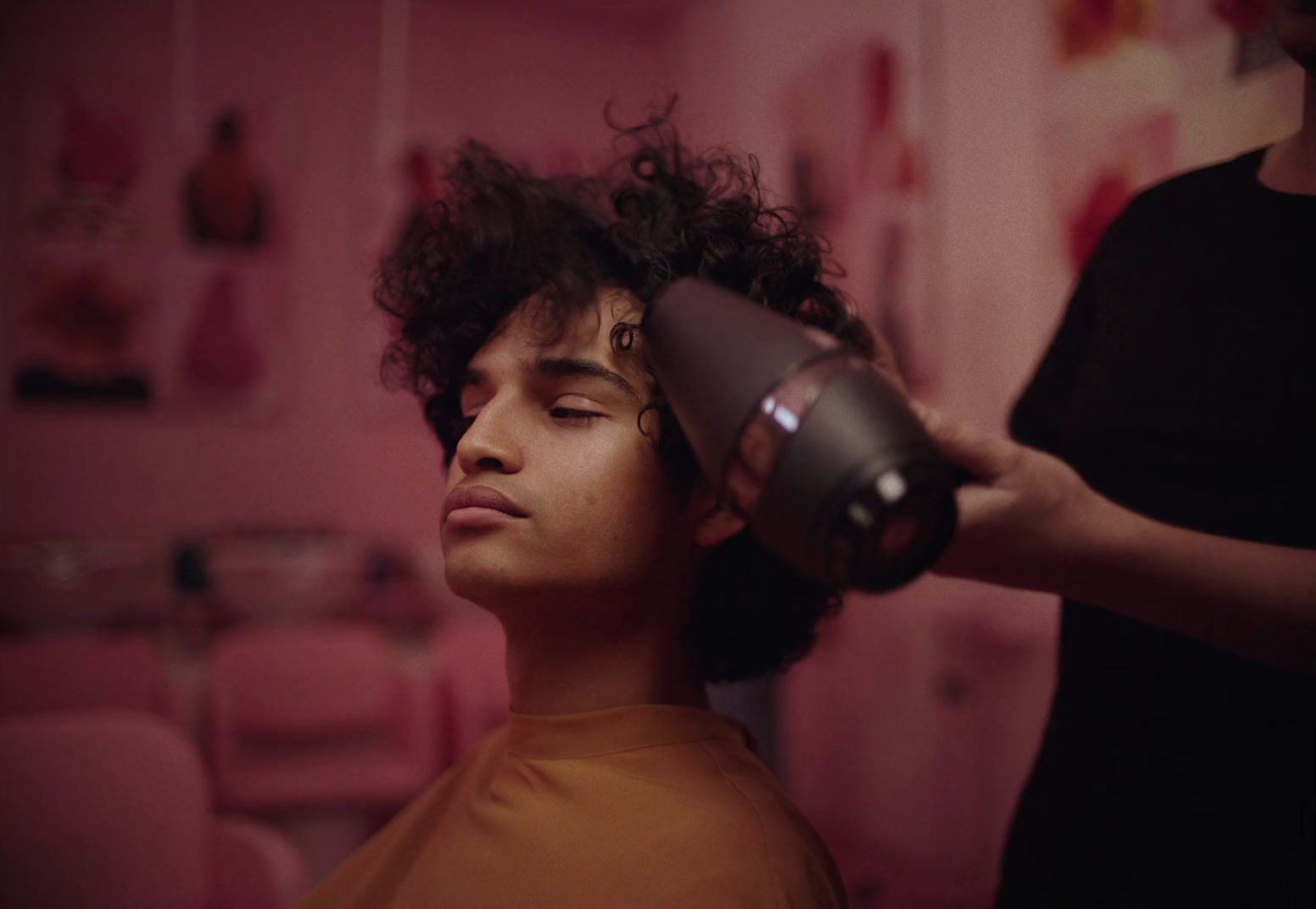 a woman blow drying a man's hair with a blow dryer