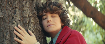 a young man is hugging a tree trunk