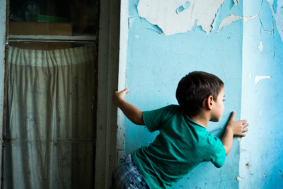 a young boy leaning against a blue wall