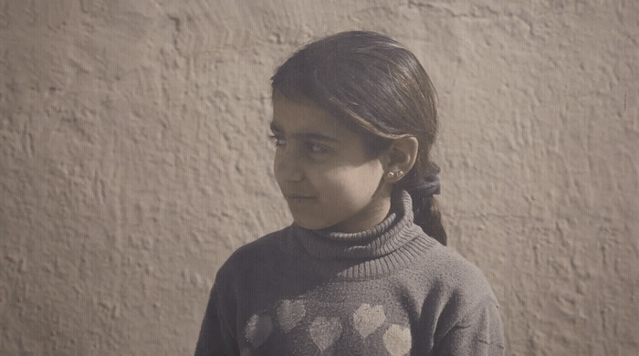 a young girl standing in front of a wall