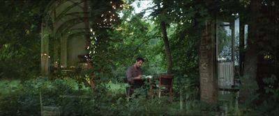 a man sitting at a table in the middle of a forest