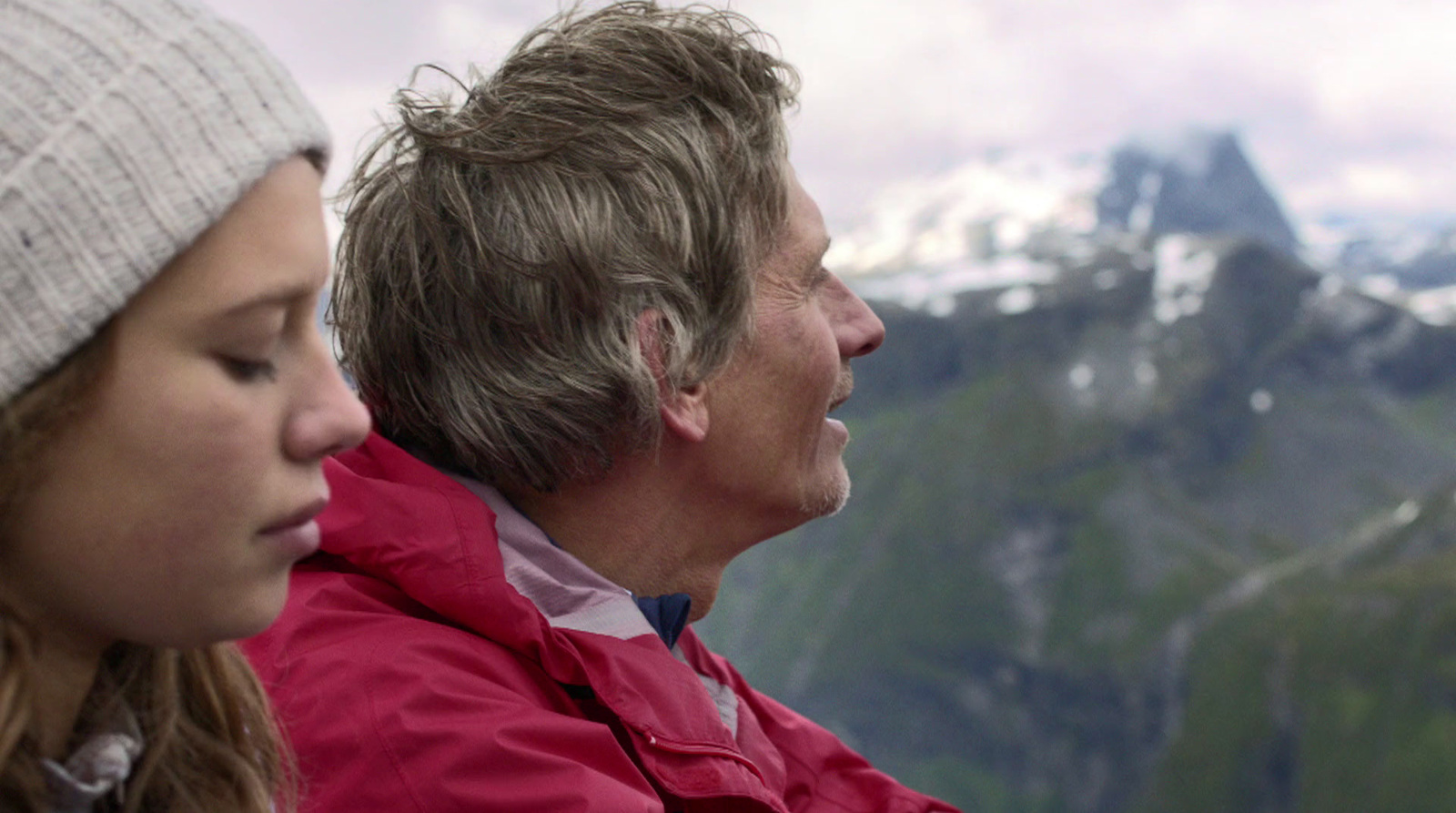 a man and a woman sitting on top of a mountain