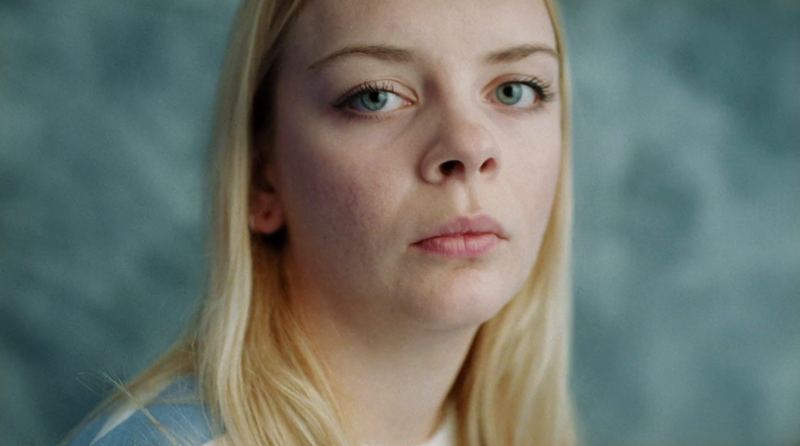 a woman with long blonde hair is looking at the camera