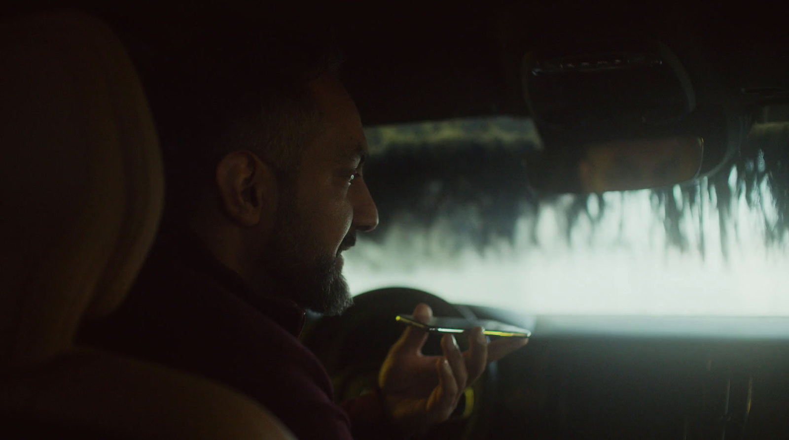 a man sitting in the back seat of a car smoking a cigarette