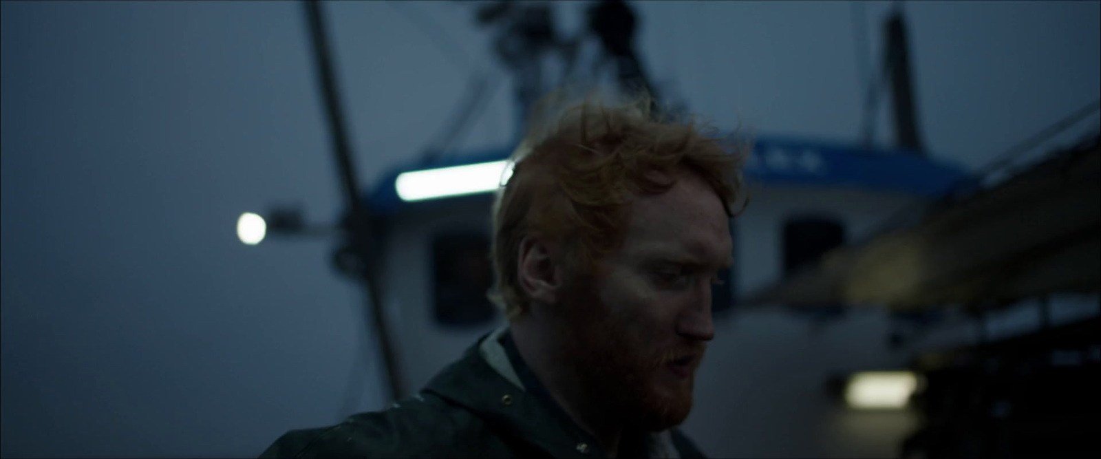 a man with red hair standing in front of a boat