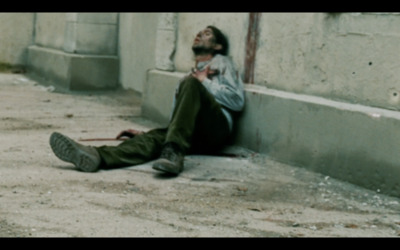 a man sitting on the ground next to a building