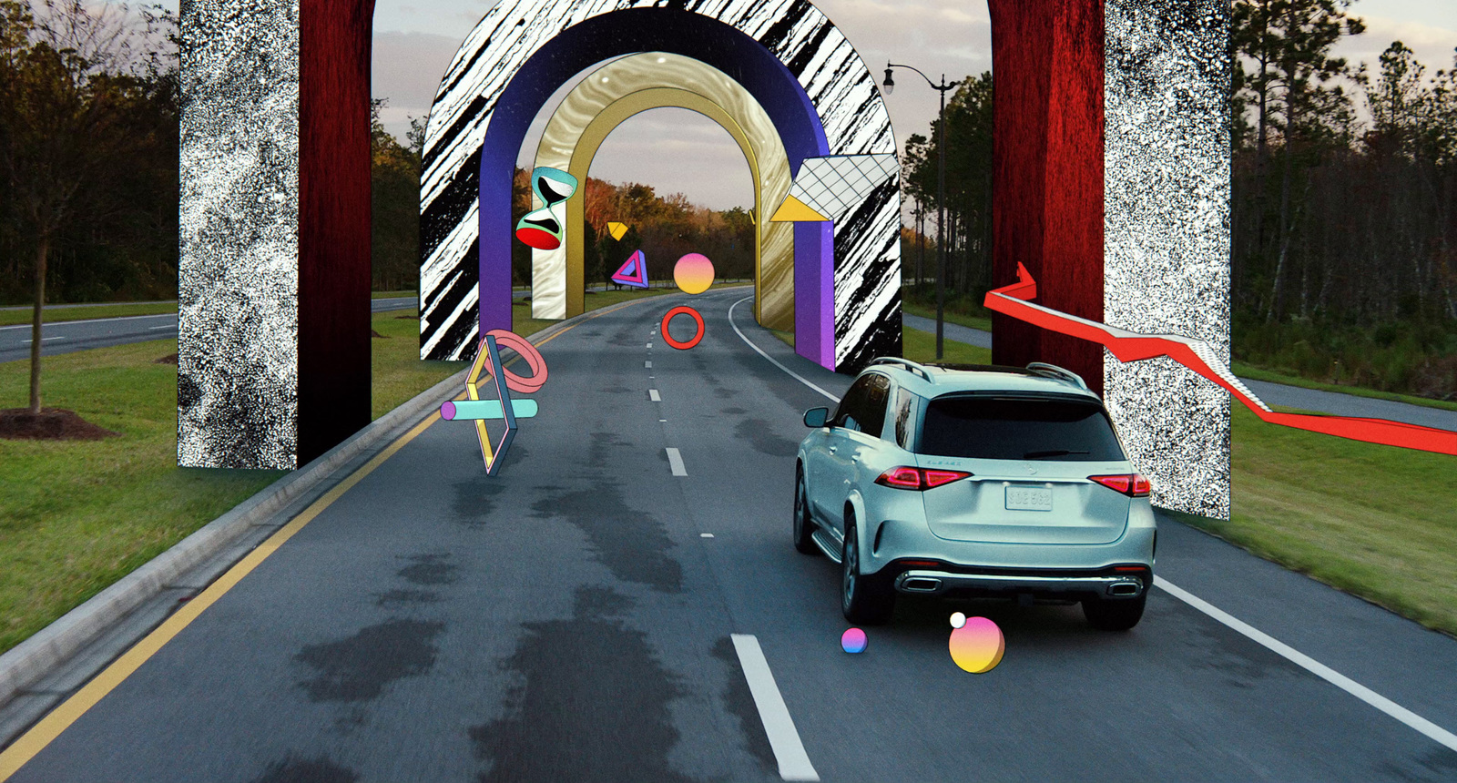 a car driving down a road next to a giant arch