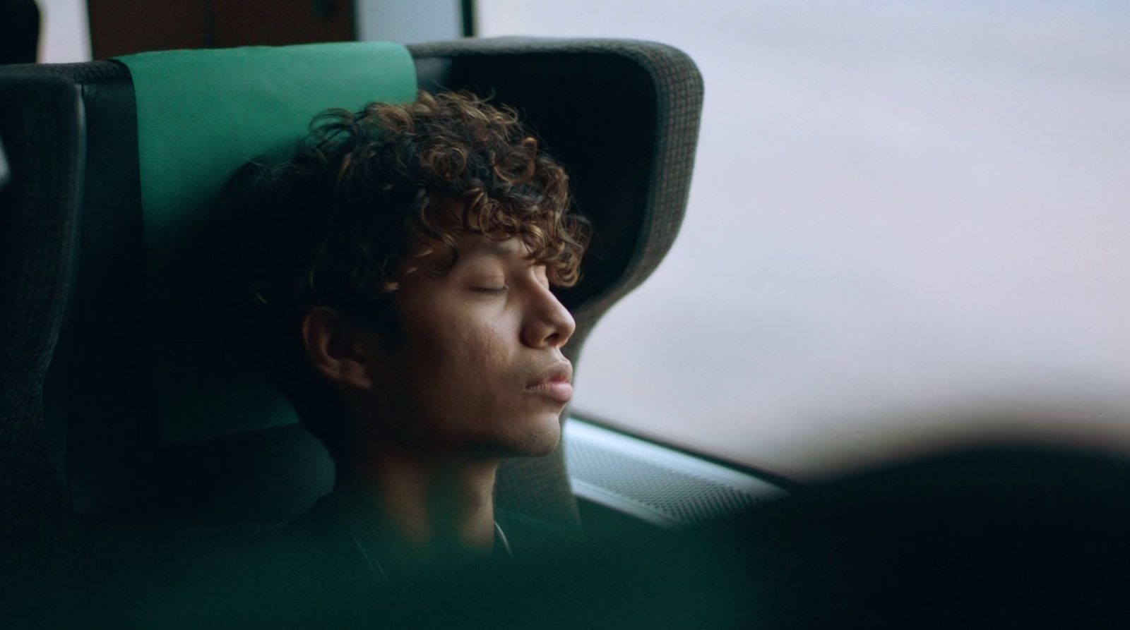 a young man sleeping on a bus seat