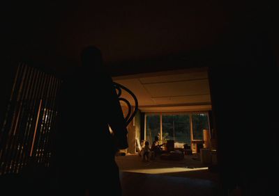 a person standing in a dark room in front of a window