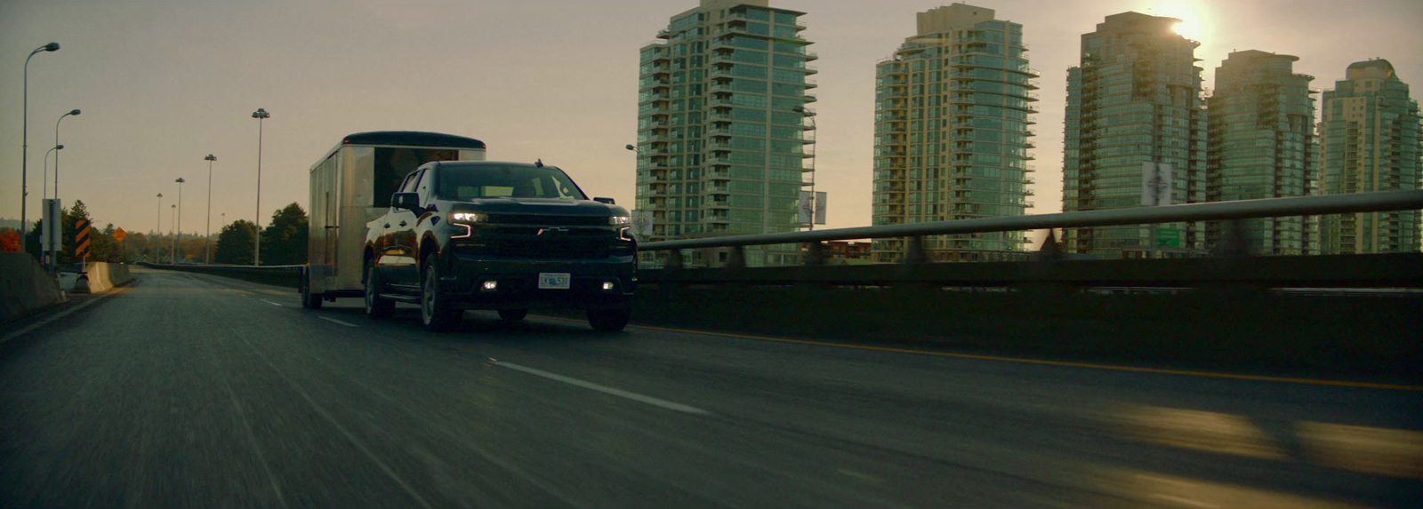 a black truck driving down a highway next to tall buildings