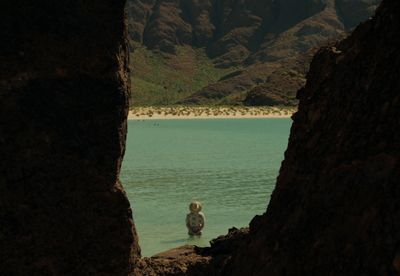 a person standing in a body of water with mountains in the background