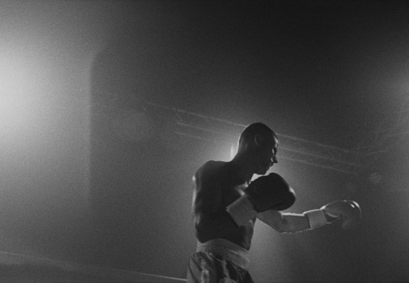 a black and white photo of a man wearing boxing gloves