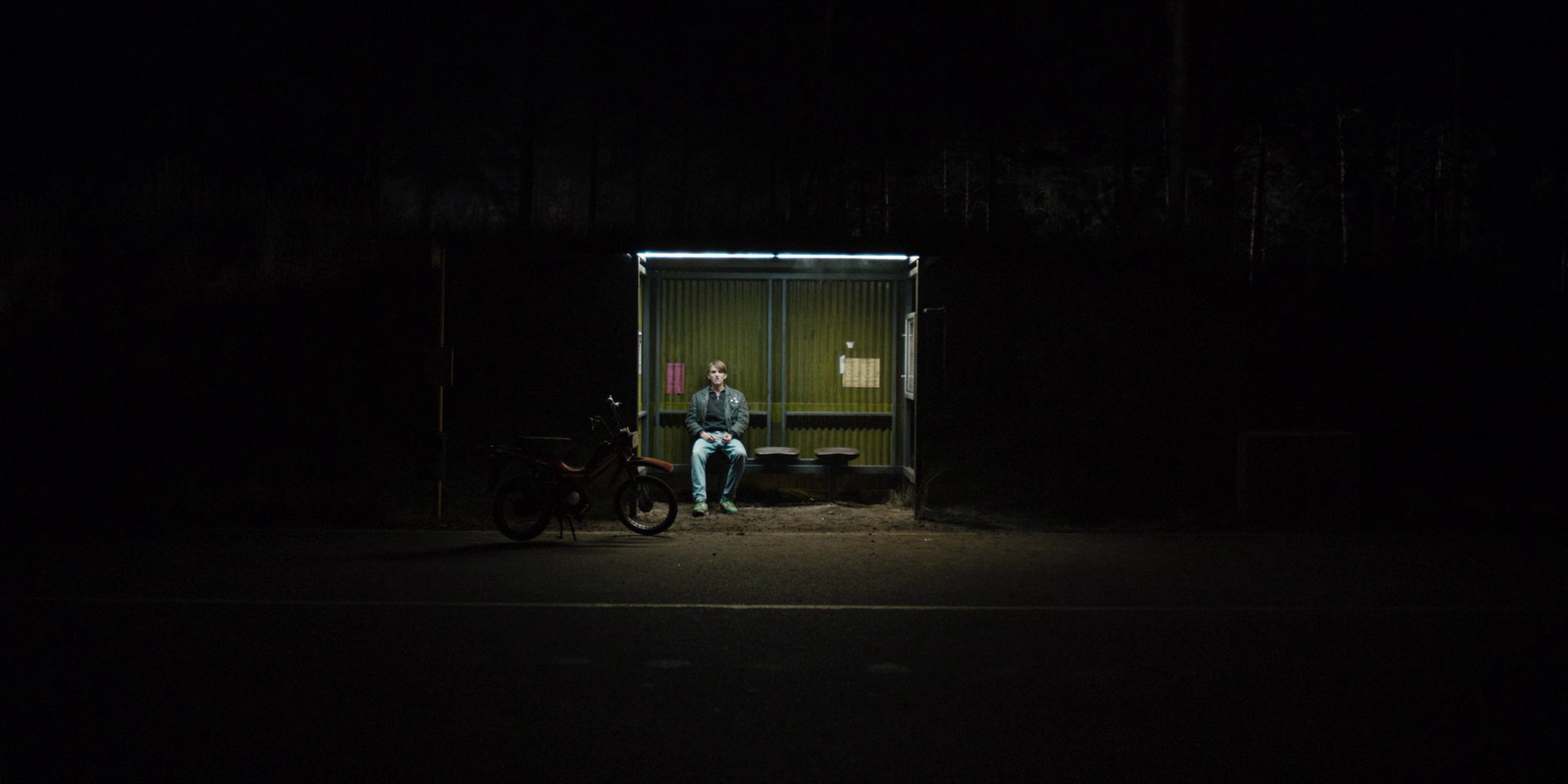 a man sitting on a bench in the dark