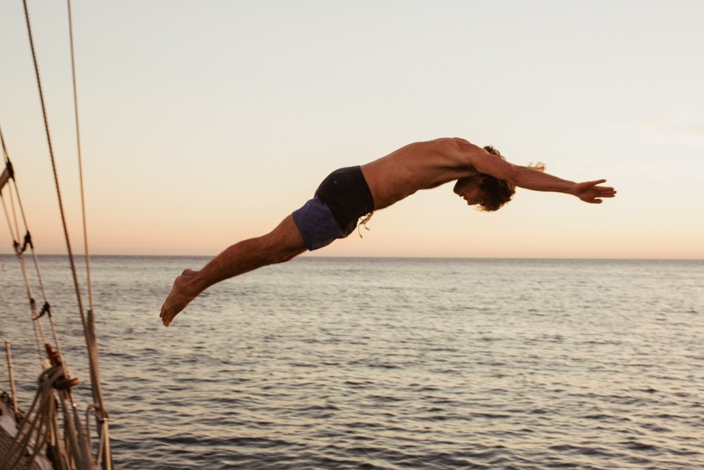 a man diving off a boat into the ocean