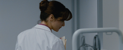 a woman in a white lab coat looking at a clipboard