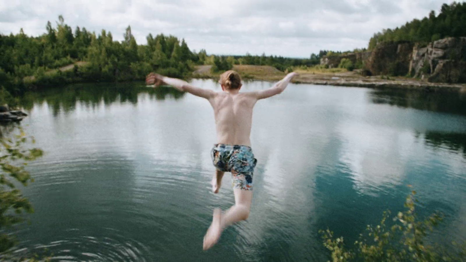 a man jumping into a lake from a cliff