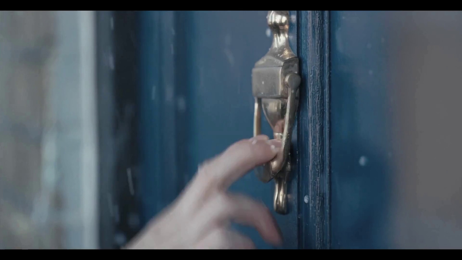 a person's hand holding a door handle on a blue door