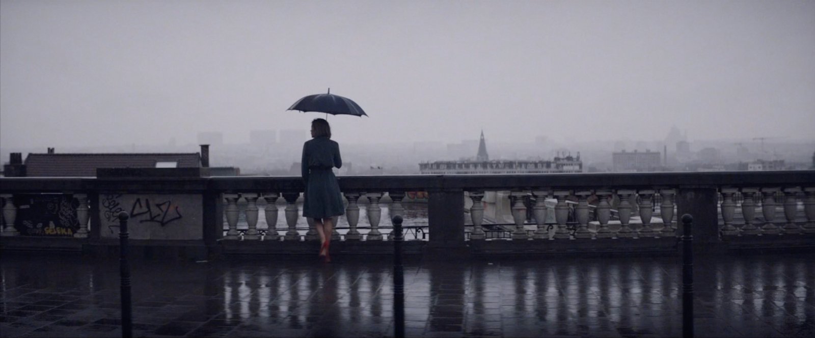 a woman standing on a bridge holding an umbrella