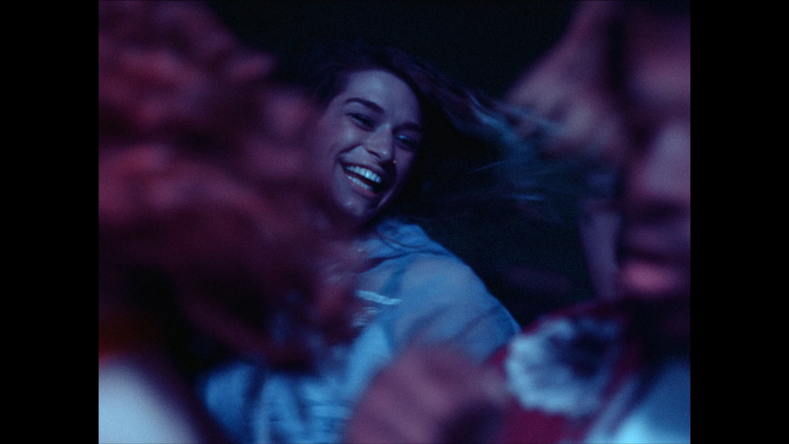 a woman laughing while standing in front of a group of people