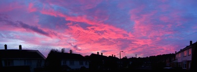 a pink and blue sky is seen over houses