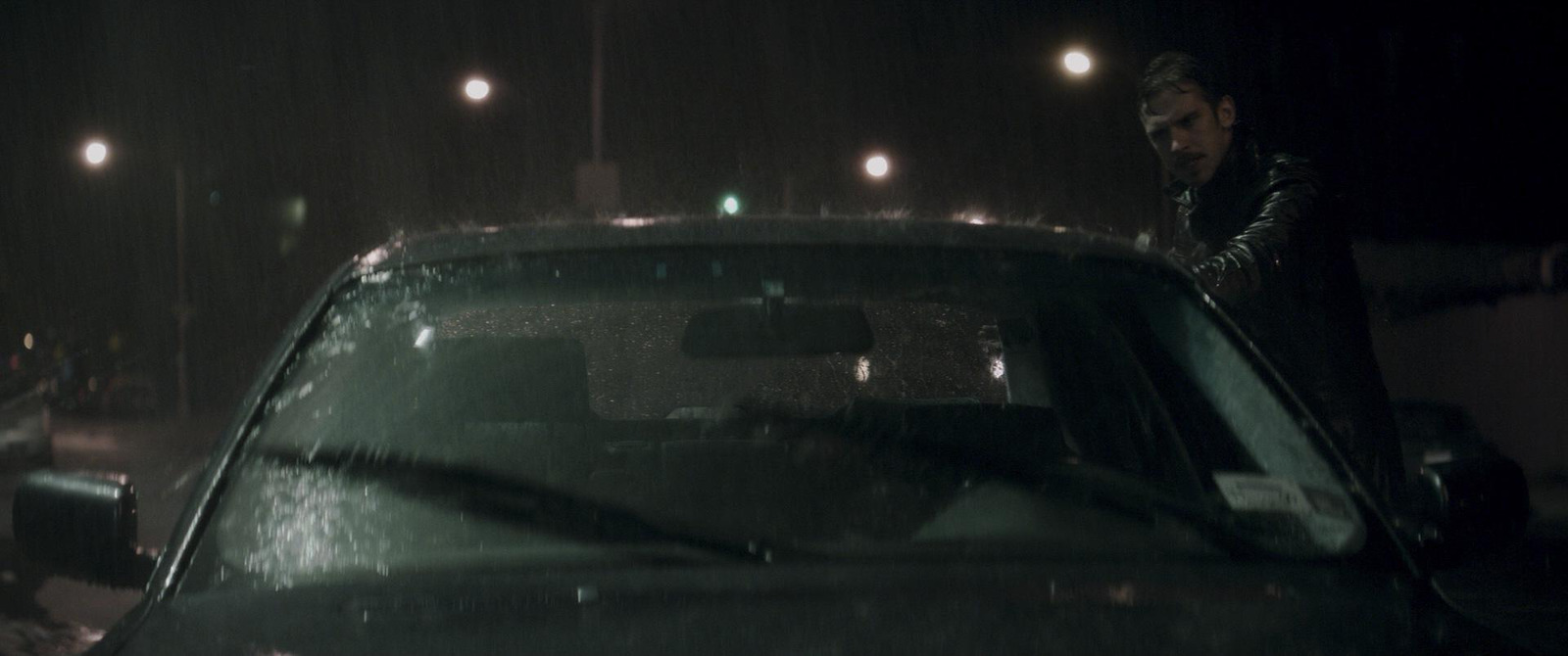 a man standing next to a car in the rain