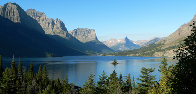 a lake surrounded by mountains with a boat in the middle