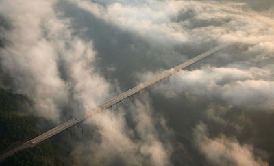 an aerial view of a bridge surrounded by clouds