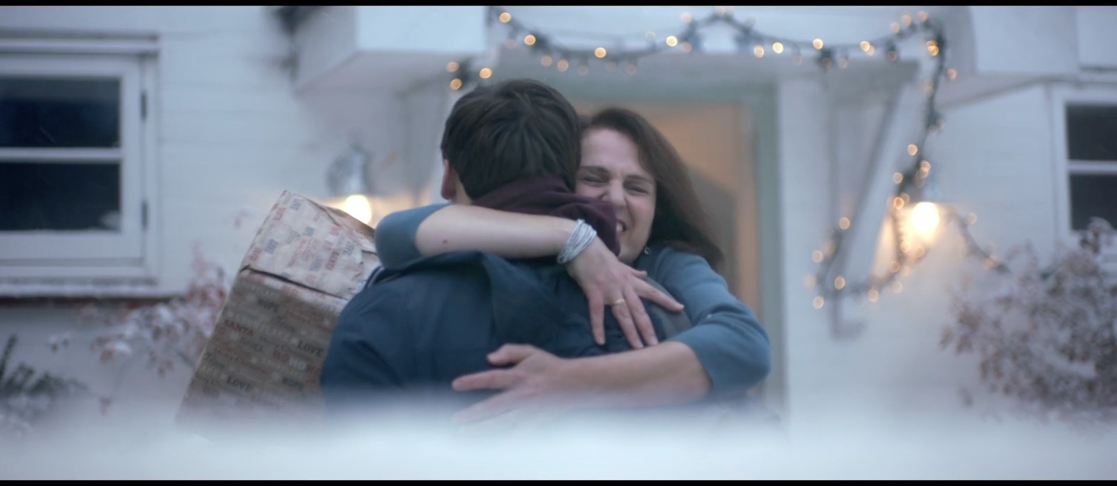 a woman hugging a man in front of a house