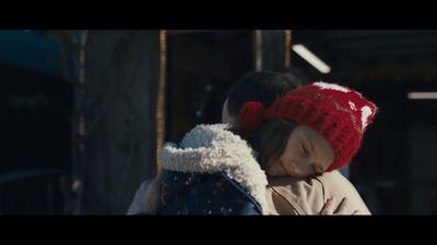 a woman holding a child wearing a red knitted hat