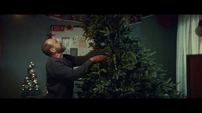 a man putting a christmas tree on top of a christmas tree