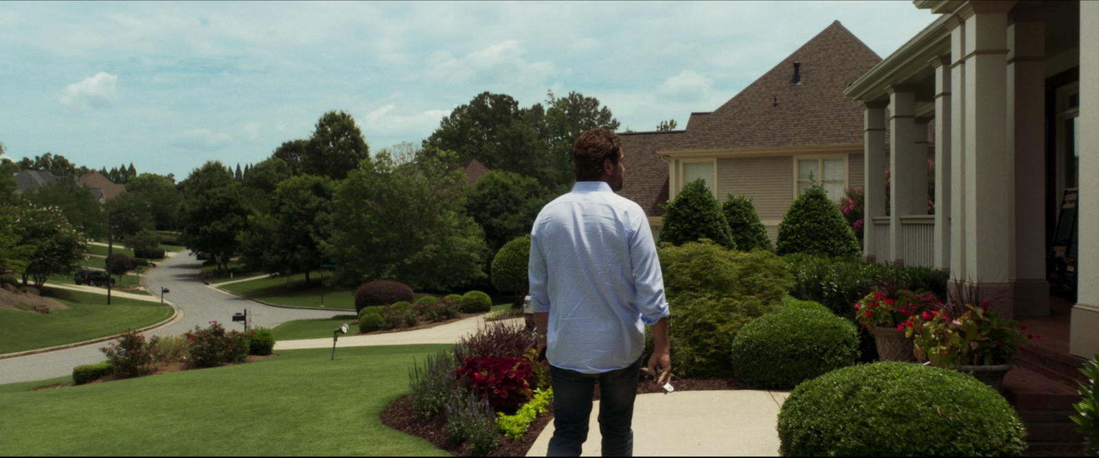 a man standing on a sidewalk in front of a house