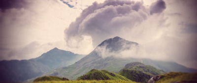 a very tall mountain with some clouds in the sky