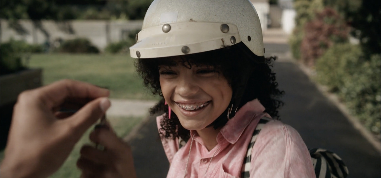 a woman in a helmet smiles while holding a cell phone