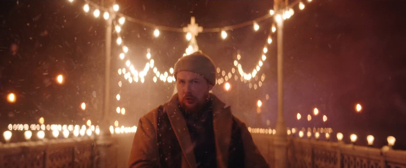 a man standing in front of a lighted bridge