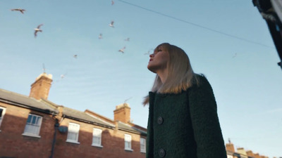 a woman looking up at a flock of birds in the sky