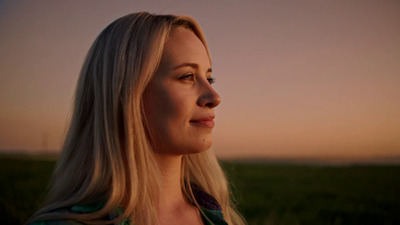 a woman standing in a field at sunset