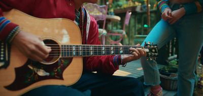 a man holding a guitar while sitting next to a woman