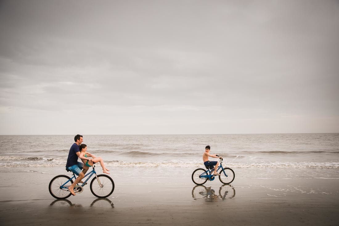 a couple of people riding bikes on top of a beach