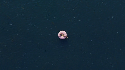 an aerial view of a person floating on a pink object in the water