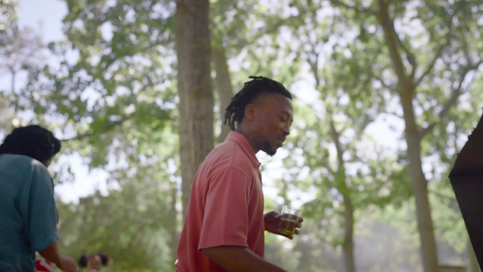 a man in a pink shirt standing in a forest