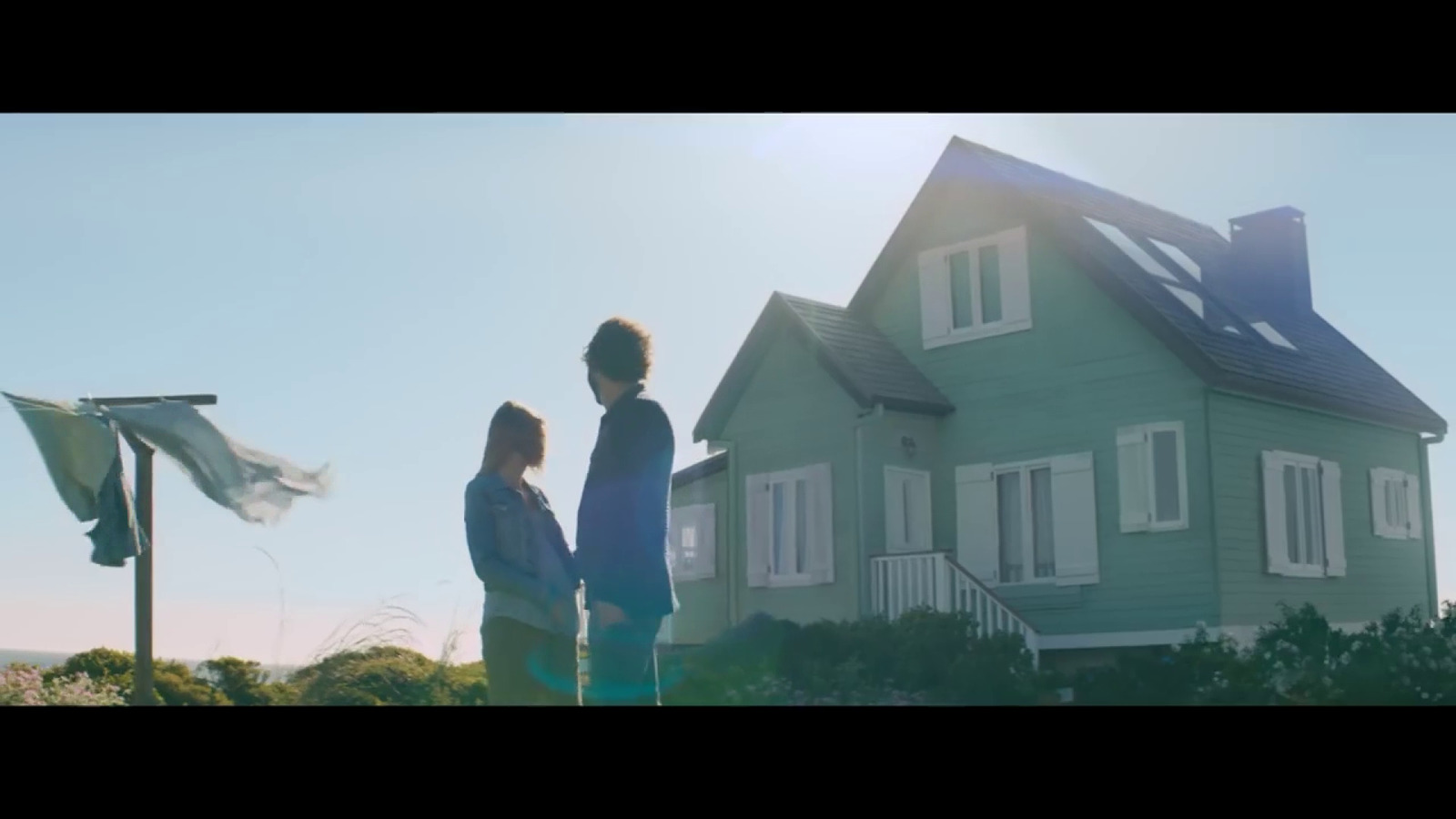 a man and a woman standing in front of a green house